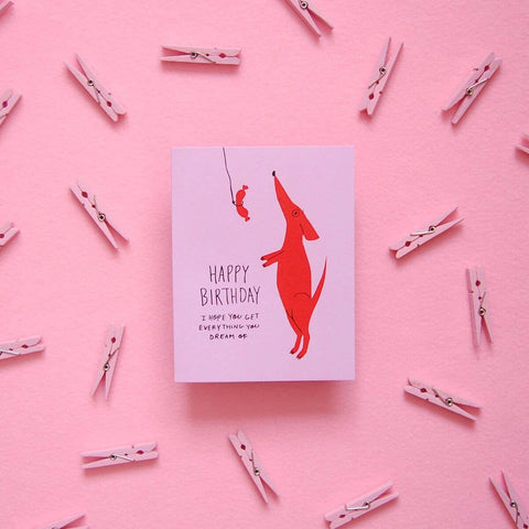 Birthday card with red dog illustration on a pink background "Happy Birthday I hope you get everything you dream of!"