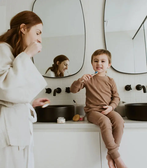 Woman and child in a bathroom brushing their teeth with toothpaste tabs
